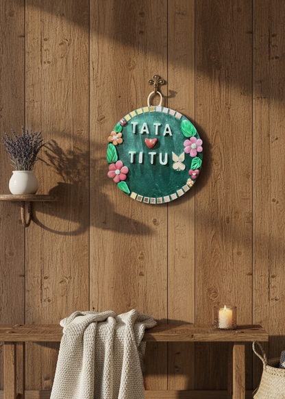 Decorative wall hanging with 'TATA TITU' text on a wooden wall.